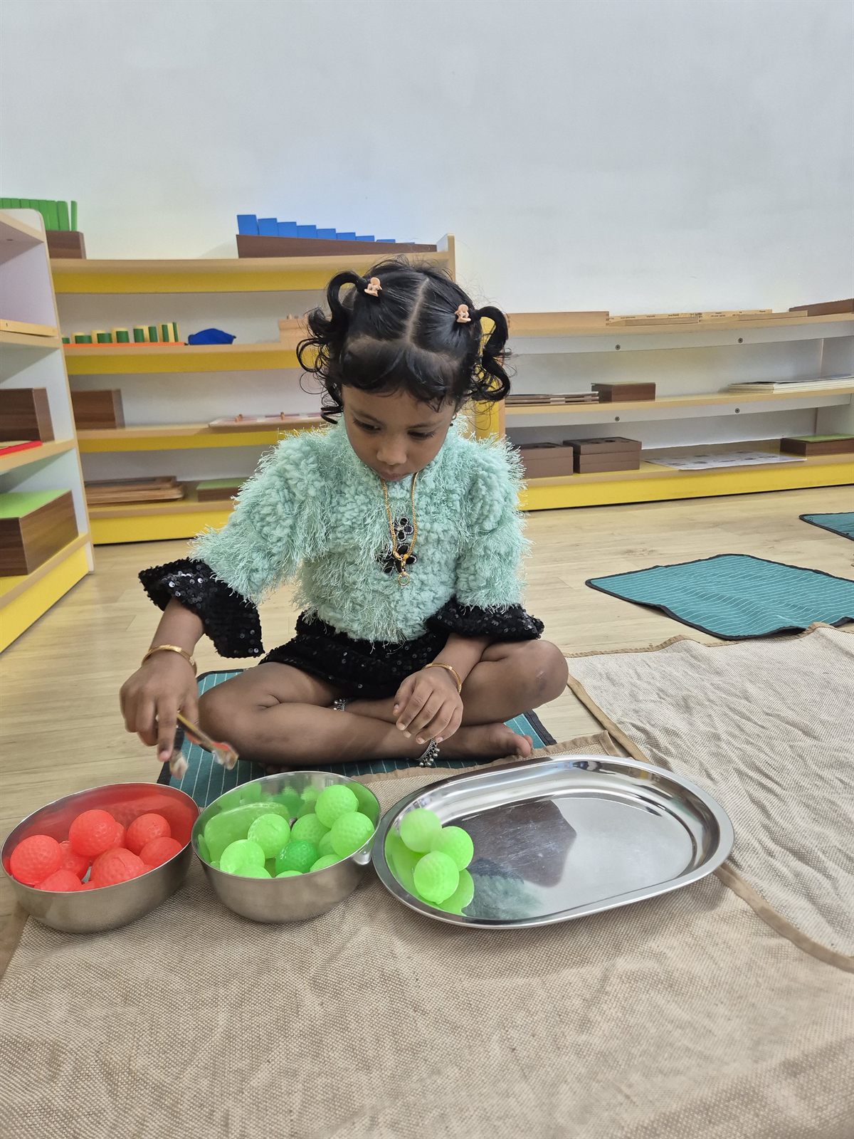 Child sorting objects on a tray during a practical-life exercise