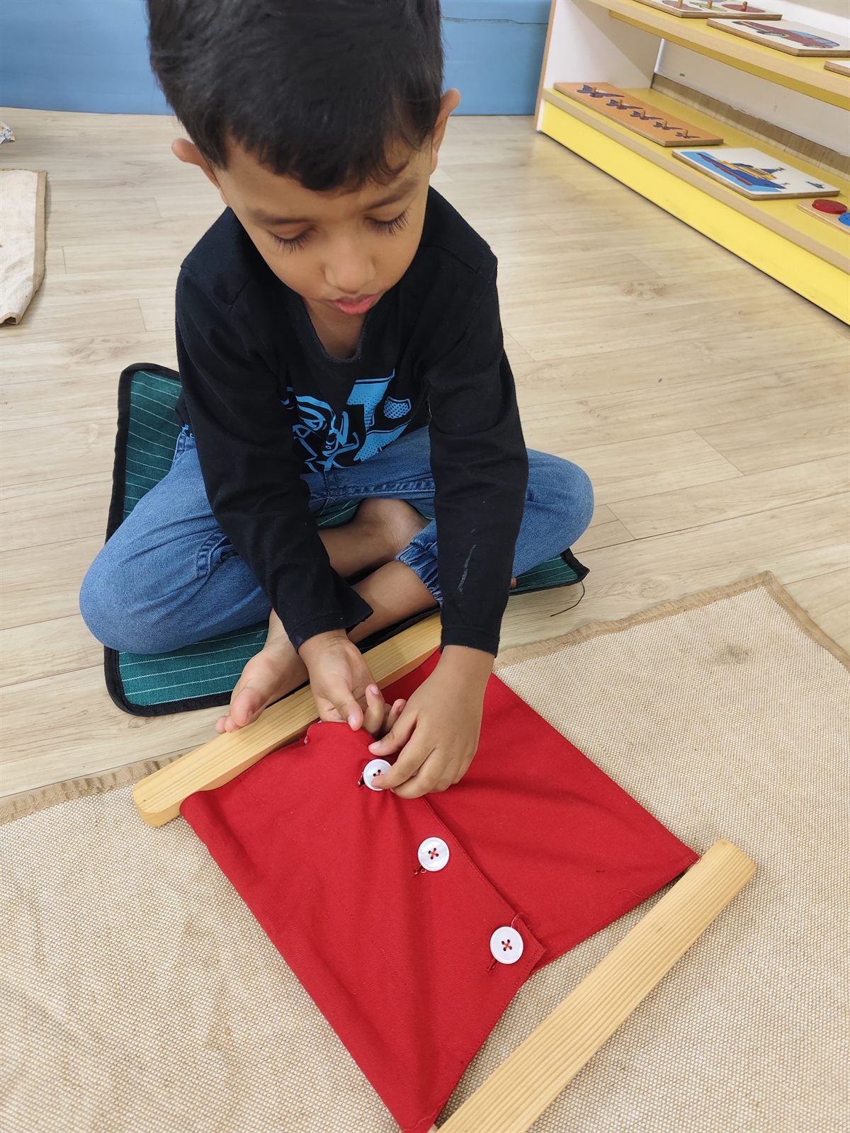 Child practising a button dressing frame, a practical-life activity